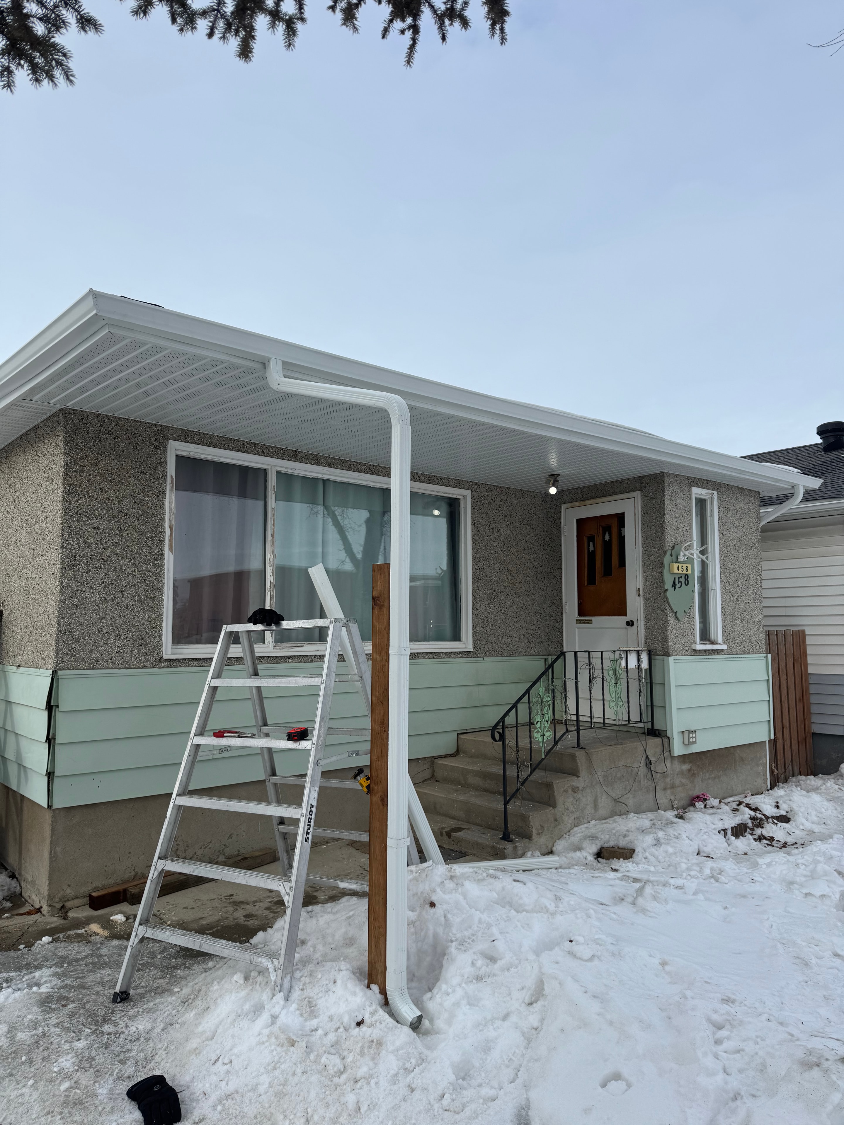 Mint green siding with white eavestrough installation Regina