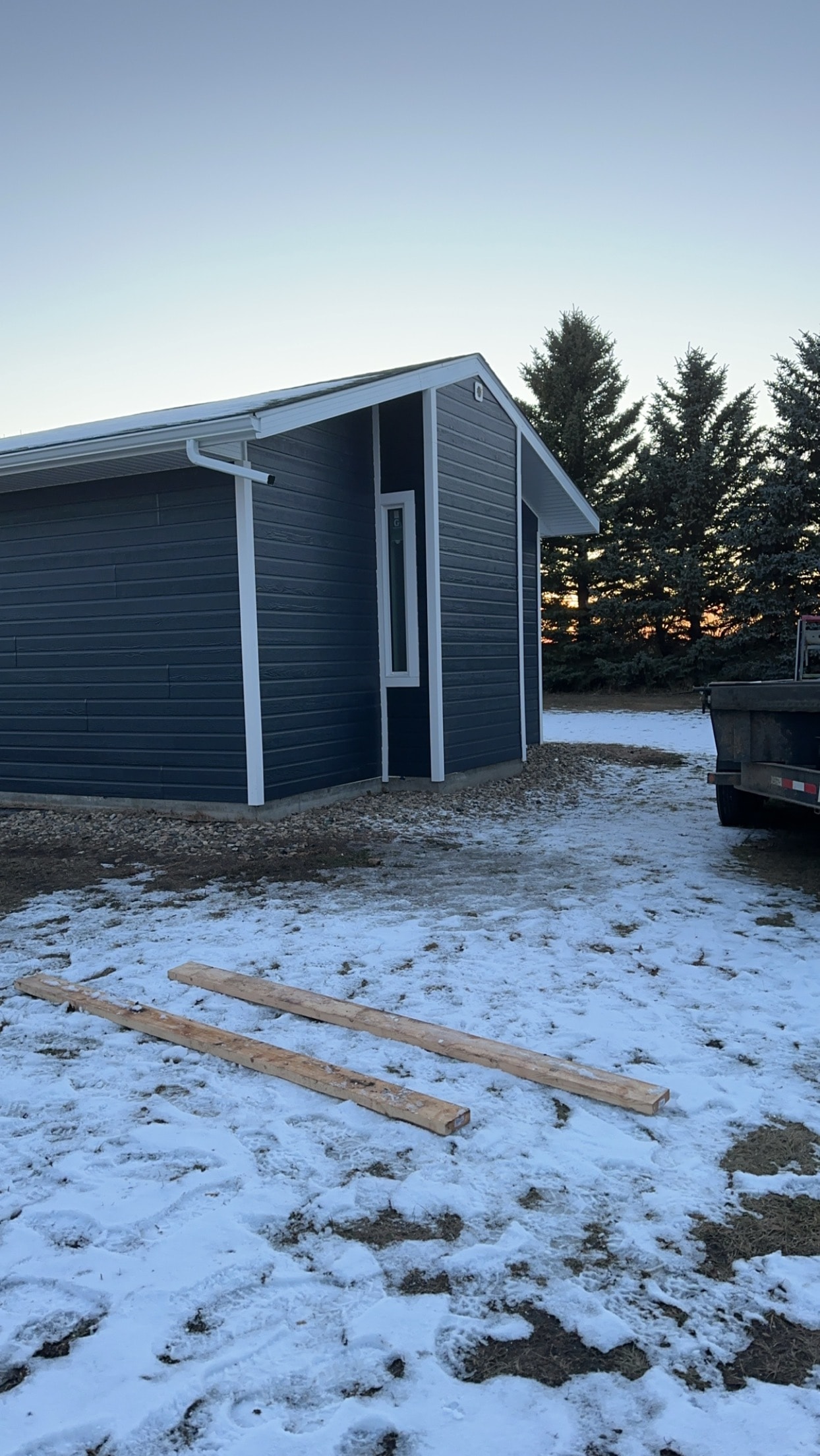 Dark navy outbuilding with white eavestrough and soffit Regina